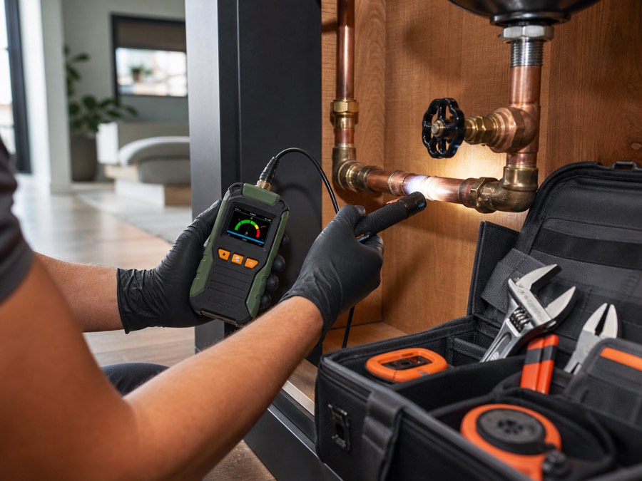 Plumbing professional using diagnostic equipment beneath a sink